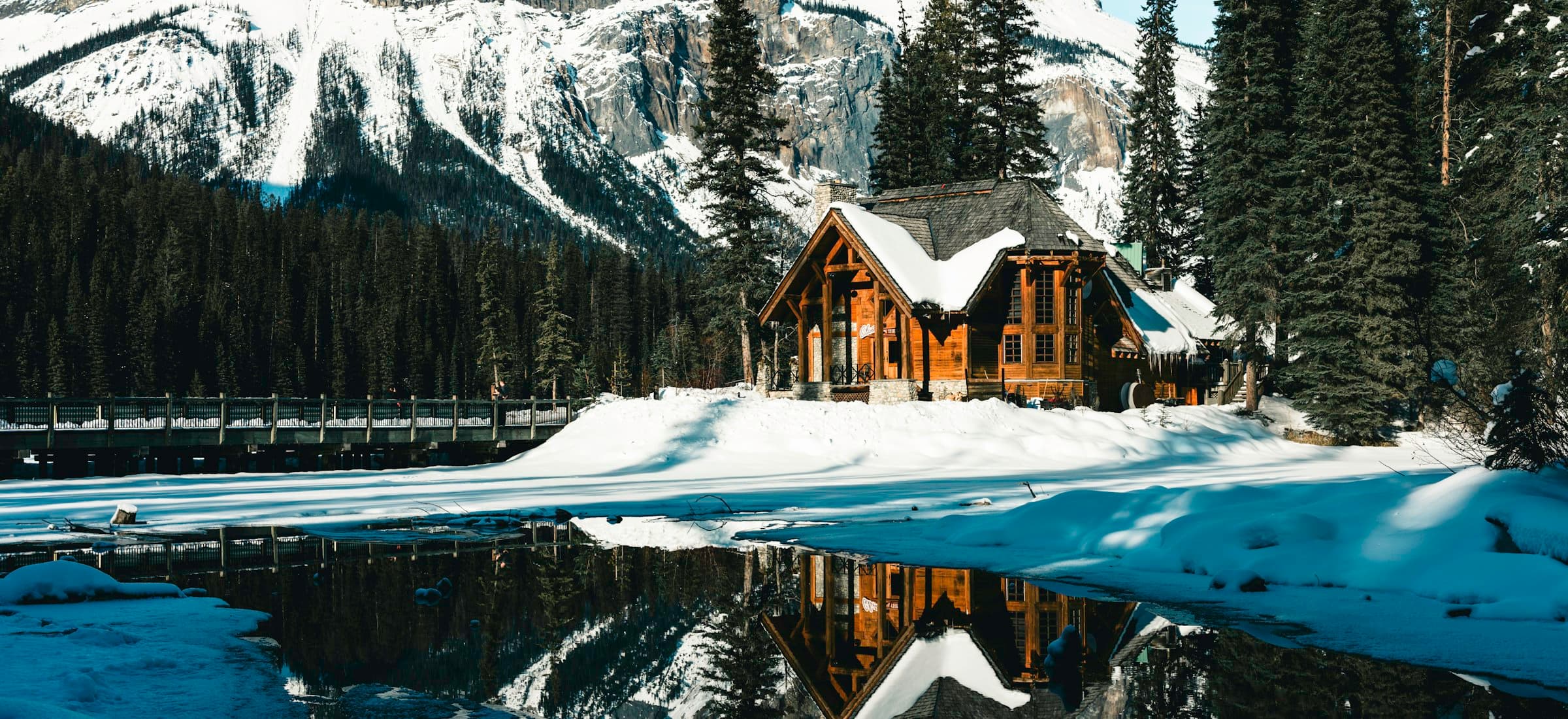 Canadian alpine lake reflecting forested mountains under clear sky